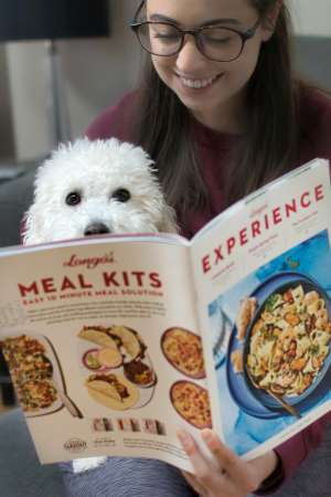 Bichon Frise reading dog food cookbook with his owner
